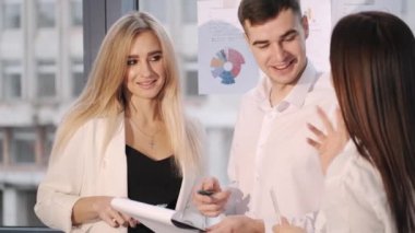 Grup og kolejleri sohbet ediyorlar ve ofiste kağıtlara bakıyorlar.