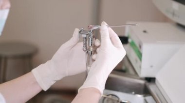 Bayan KBB doktoru bir kutudan aletleri alıyor ve hastasını muayene ediyor.