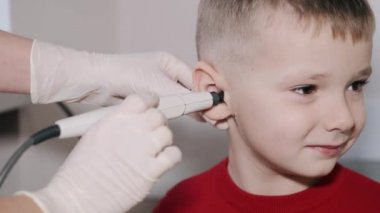 Otolaryngologist ofiste bir çocuğun kulağını inceliyor.