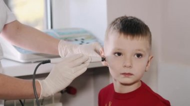 Otolaryngologist ofiste bir çocuğun kulağını inceliyor.