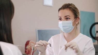 Doktor kadın hastaya işitme cihazı gösteriyor.