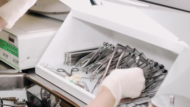Женщина ЛОР врач берет инструменты из коробки и собирается осмотреть своего пациента — стоковое видео
