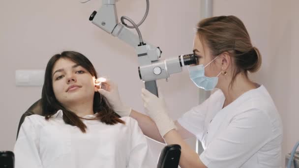 Dokter onderzoekt het oor van een jonge vrouw in de kliniek — Stockvideo