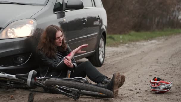 Молодая женщина упала на землю с кровоточащей царапиной на руке — стоковое видео