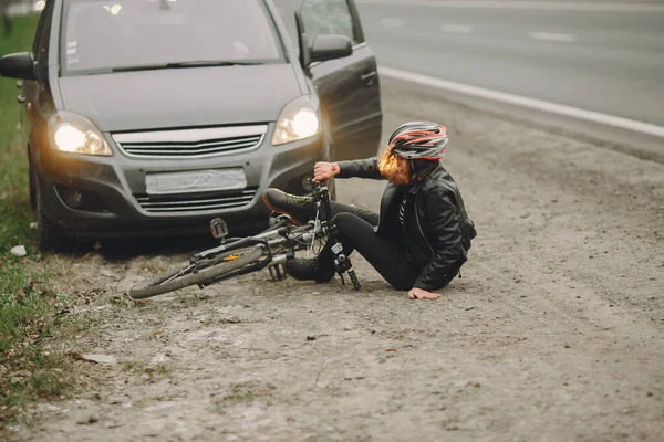 Kecelakaan di jalan dengan pengendara sepeda wanita dan mobil — Stok Foto