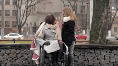 Kızı dışarıda özürlü annesiyle kucaklaşıyor.