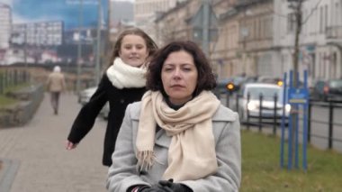 Okullu kız, engelli annesine bir şehirde asfaltta yaklaşıyor.