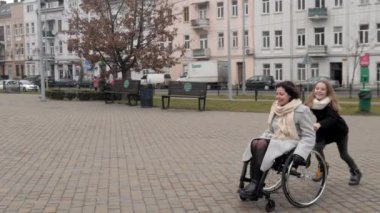 Tekerlekli sandalyedeki kadın kızıyla dışarıda eğleniyor.