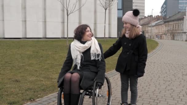 Putri kecil berjalan dengan ibunya cacat di sebuah kota — Stok Video