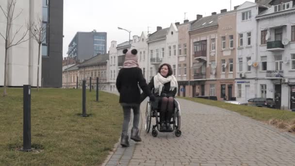 Школярка наближається до своєї матері-інваліда на тротуарі в місті — стокове відео