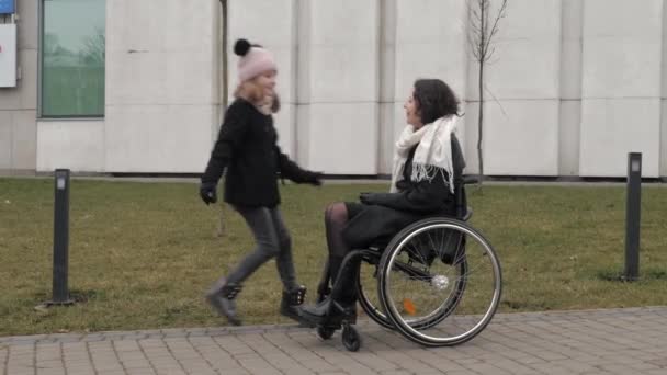 Iskoláslány közeledik fogyatékos anyjához a járdán egy városban. — Stock videók