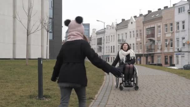 Schoolmeisje nadert haar gehandicapte moeder op de stoep in een stad — Stockvideo