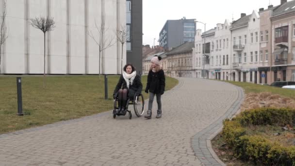 Маленька дочка гуляє з матір'ю-інвалідом у місті — стокове відео