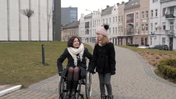 A kislánya a fogyatékos anyjával sétál egy városban. — Stock videók
