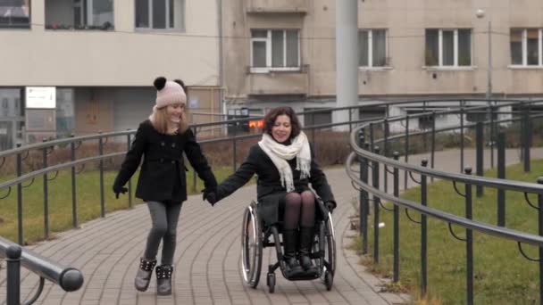 Little daughter walking with her handicapped mother in a city — Stock Video