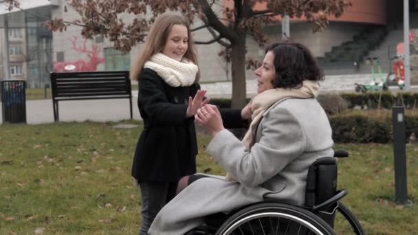 휠체어를 타고 딸과 밖에서 즐거운 시간을 보내고 있는 여자 — 비디오
