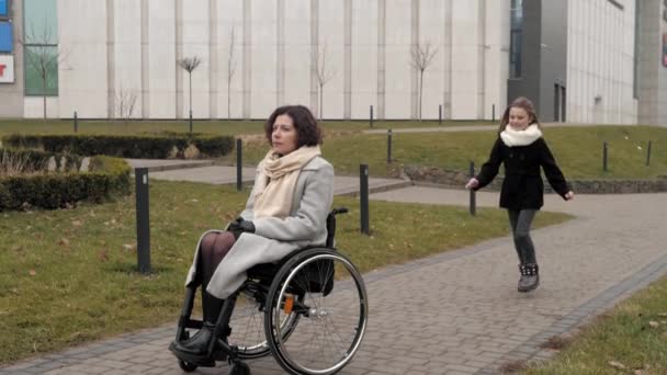 Colegiala acercándose a su madre discapacitada en el pavimento de una ciudad — Vídeo de stock