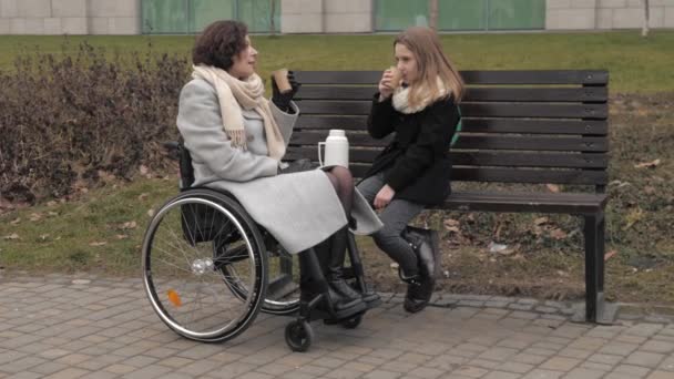 Skolflicka med sin handikappade mamma dricka te utanför — Stockvideo