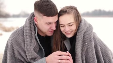 Kareli kumaşa sarılı sevgili çift kışın dışarıda oturuyor.