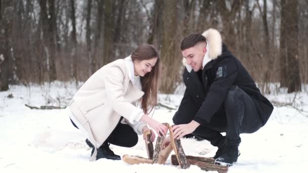 Jeune couple faisant feu de camp près de la forêt en hiver — Video