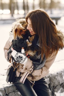 Genç bir kadın köpeğine sarılıyor.