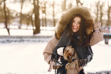 Genç bir kadın köpeğine sarılıyor.