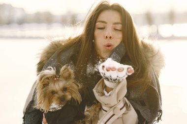 Genç bir kadın köpeğine sarılıyor.