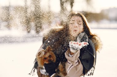 Genç bir kadın köpeğine sarılıyor.