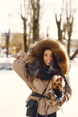 Genç bir kadın köpeğine sarılıyor.