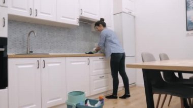 Kadın hademe mutfaktaki yemek panelini temizliyor.