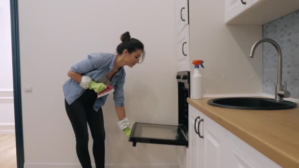 Jovem mulher limpando forno na cozinha — Vídeo de Stock