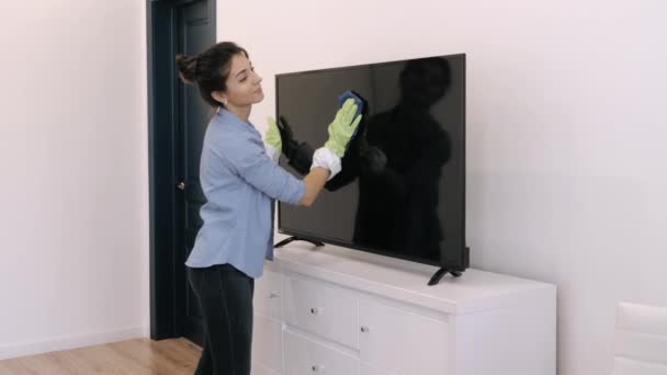 Kobieta wycierająca ekran telewizora w domu — Wideo stockowe