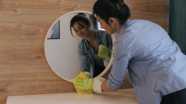 Młoda kobieta z serwisu sprzątania wycierania lustra w domu — Wideo stockowe