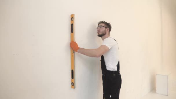 Hombre en nivel de pared de medición uniforme con una herramienta — Vídeos de Stock