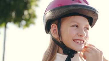 Genç anne kızına dışarıda kask takması için yardım ediyor.