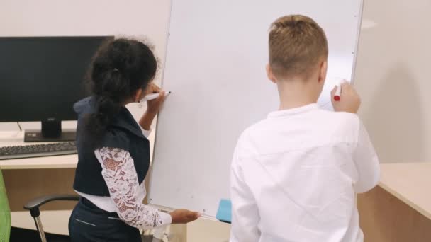 Schulkinder schreiben auf einer weißen Tafel in einem Klassenzimmer — Stockvideo