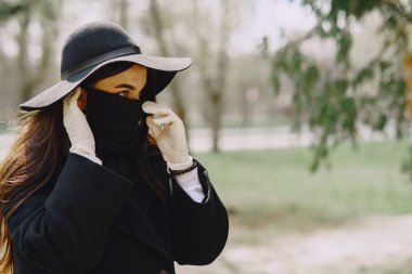 Maskeli kadın sokakta duruyor.