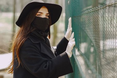 Maskeli kadın sokakta duruyor.