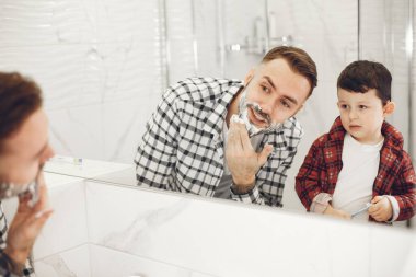 Oğlu ve babası banyo aynasında tıraş oluyor.