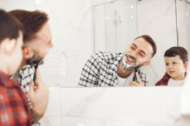 Oğlu ve babası banyo aynasında tıraş oluyor.
