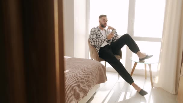 Młody mężczyzna odpoczywa z phoen i kawą w domu — Wideo stockowe