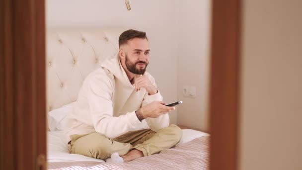 Jovem deitado na cama e assistindo tv em casa — Vídeo de Stock