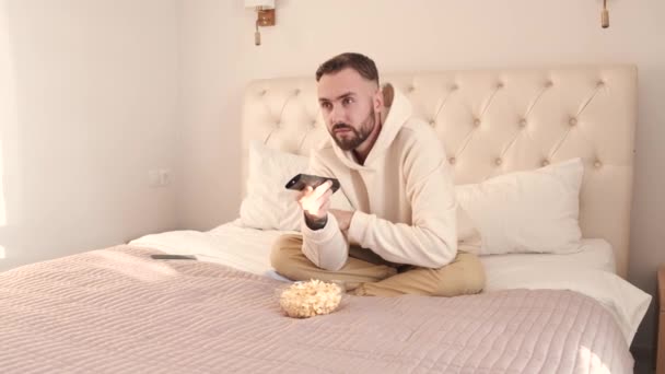 Jovem deitado na cama e assistindo tv em casa — Vídeo de Stock