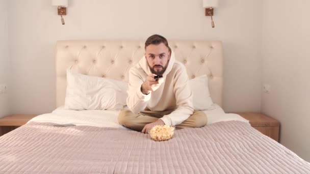 Joven acostado en la cama y viendo la televisión en casa — Vídeos de Stock