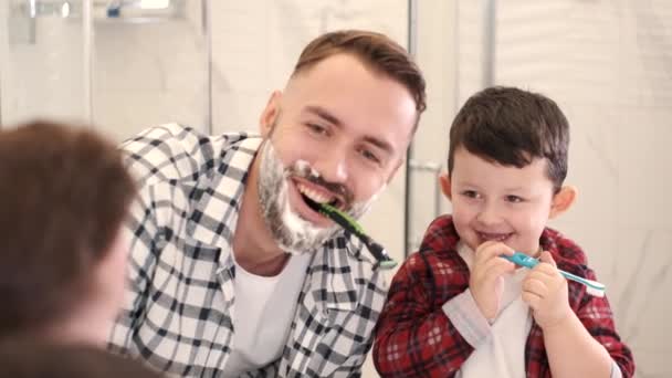 Homem pai ensina seu filho o menino no banheiro escovando dentes — Vídeo de Stock