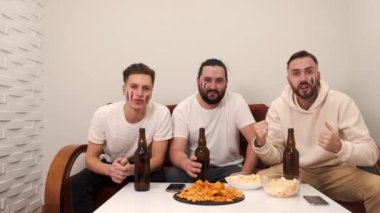 Bir grup mutlu arkadaş televizyonda bira eşliğinde maç izliyorlar.