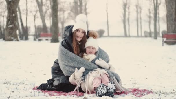 Μητέρα και κόρη κάνουν πικνίκ σε κουβέρτα στο χειμερινό πάρκο — Αρχείο Βίντεο