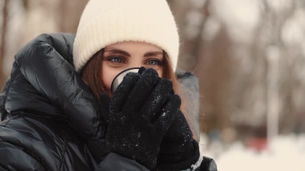 Mulher de casaco preto puffer e chapéu beber café ou chá de copo de garrafa térmica — Vídeo de Stock