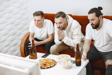 Bir grup taraftar televizyonda bir futbol maçı izliyorlar.