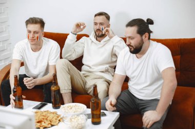 Bir grup taraftar televizyonda bir futbol maçı izliyorlar.